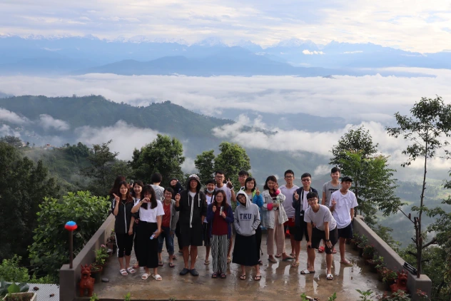 Guests from Taiwan pose in front of the farmhouse on a rainy day, overlooking the himalayas